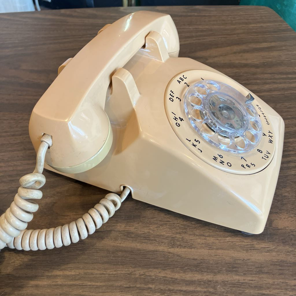 Beige rotary phone on a wooden surface