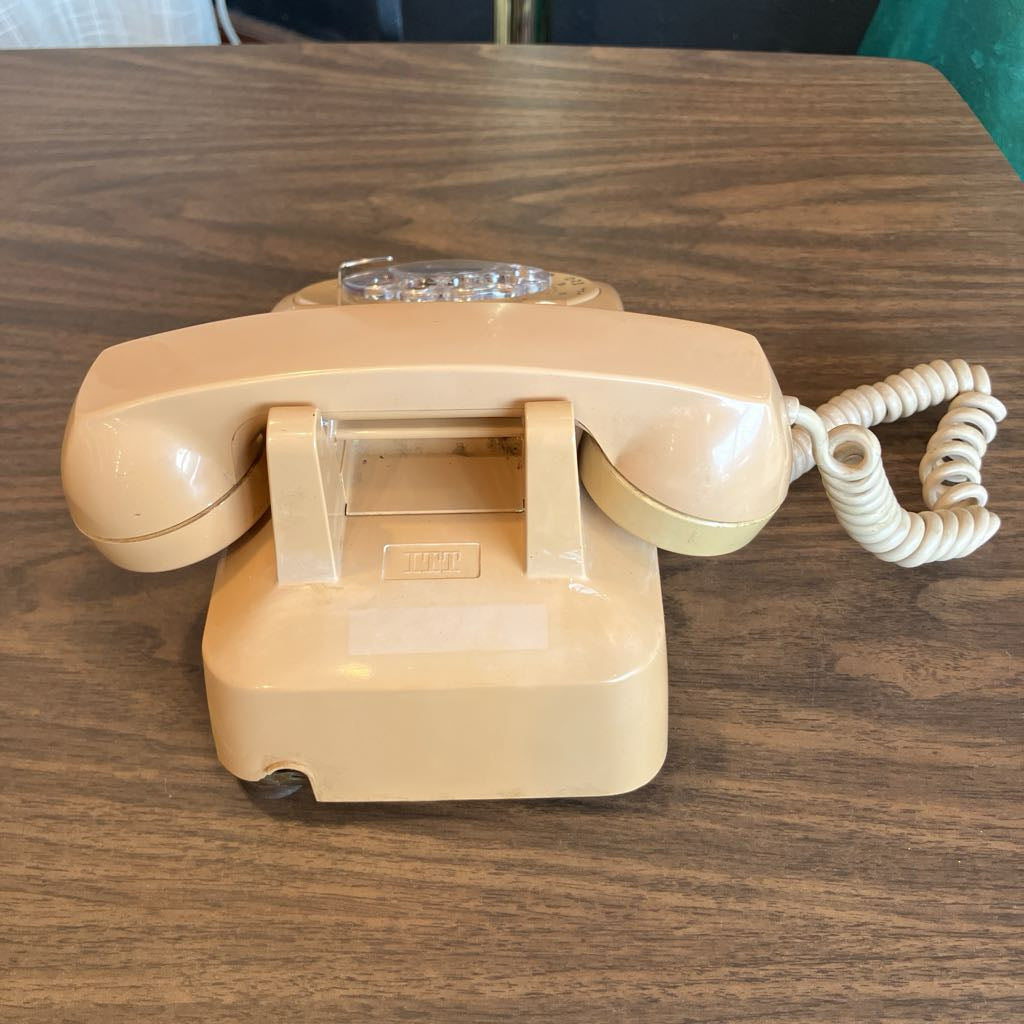 Beige rotary phone on a wooden surface
