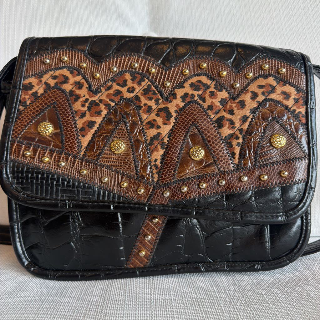 Handbag with leopard print and black leather design on a light gray background