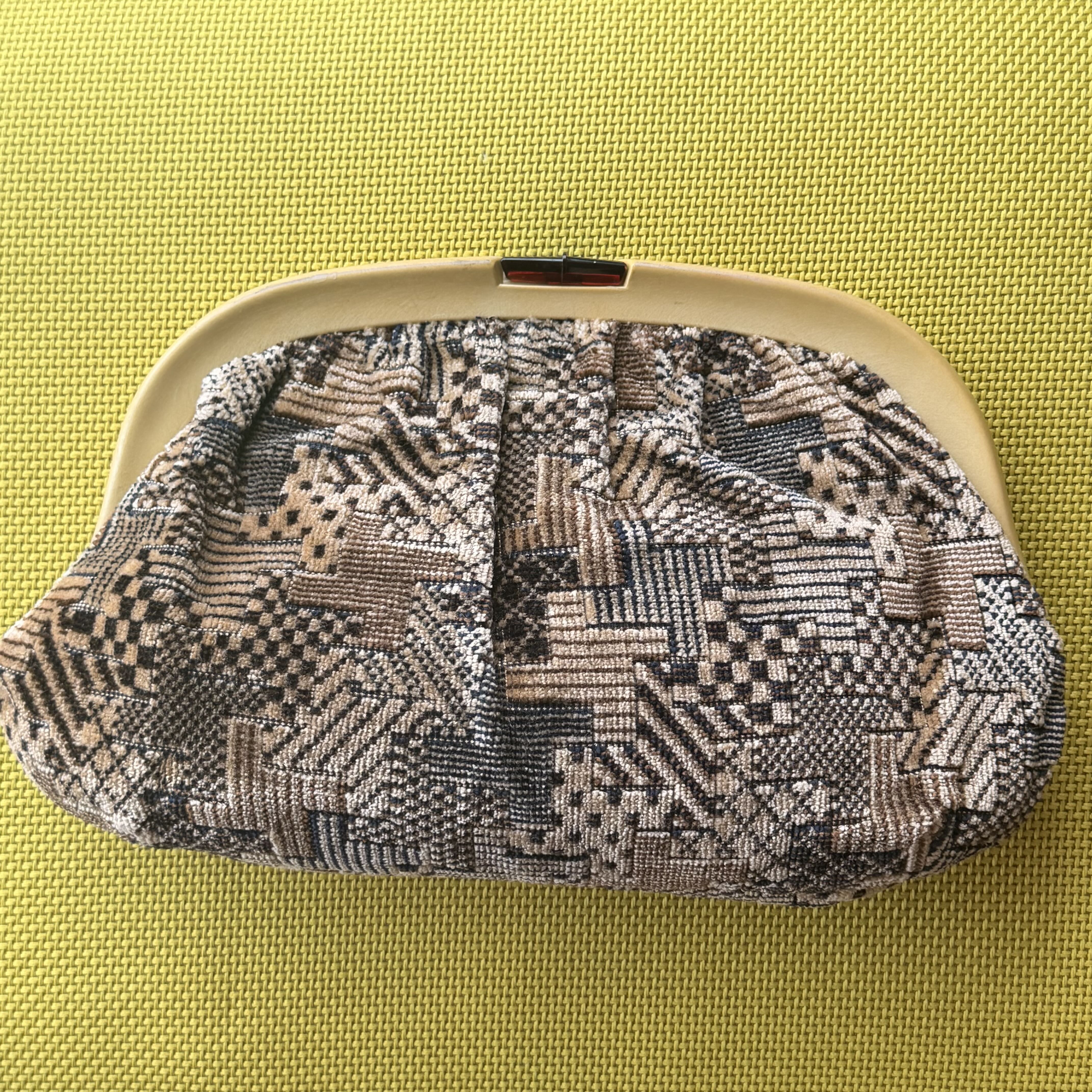 Patterned fabric on a beige frame against a green background