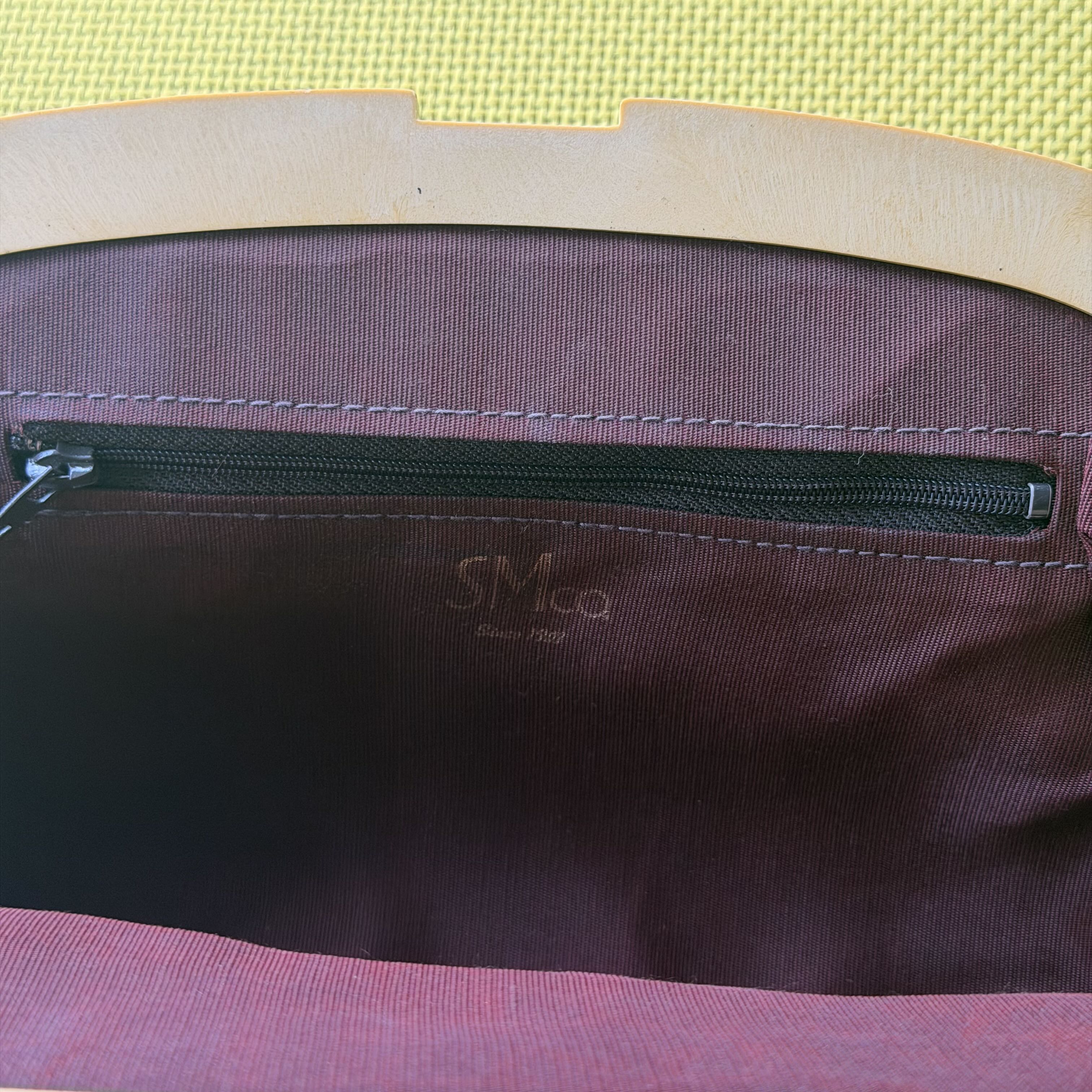 Close-up of a purple bag with a zipper and 'Snoo' branding on a yellow background