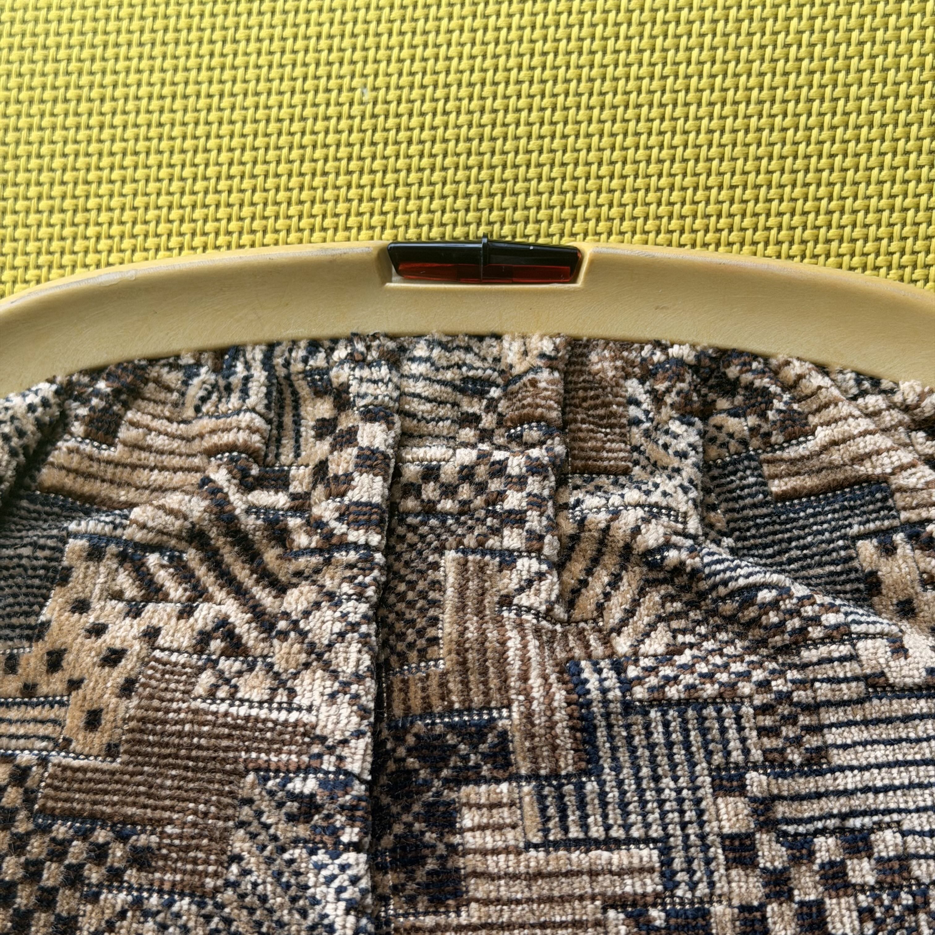 Close-up of a geometric patterned fabric inside an embroidery hoop on a yellow background