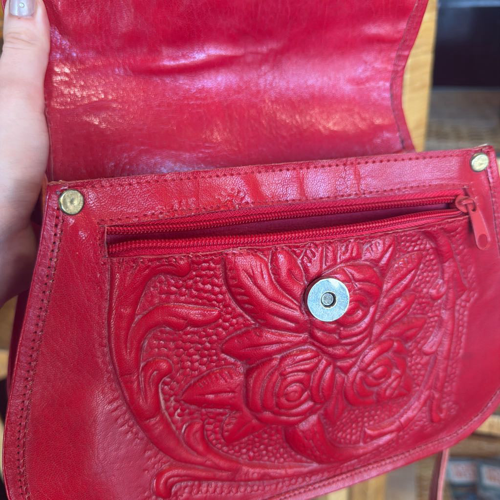 Red leather wallet with intricate embossed design held by a hand.