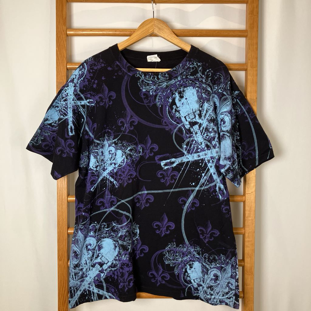 Black t-shirt with blue and purple abstract designs on a wooden hanger against a white wall.