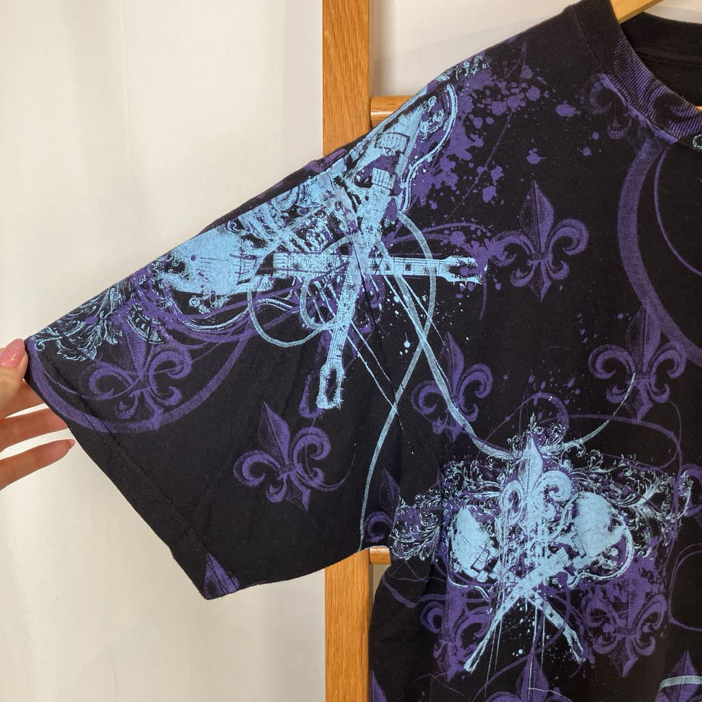 Black shirt with blue and white floral patterns on a wooden hanger against a white background