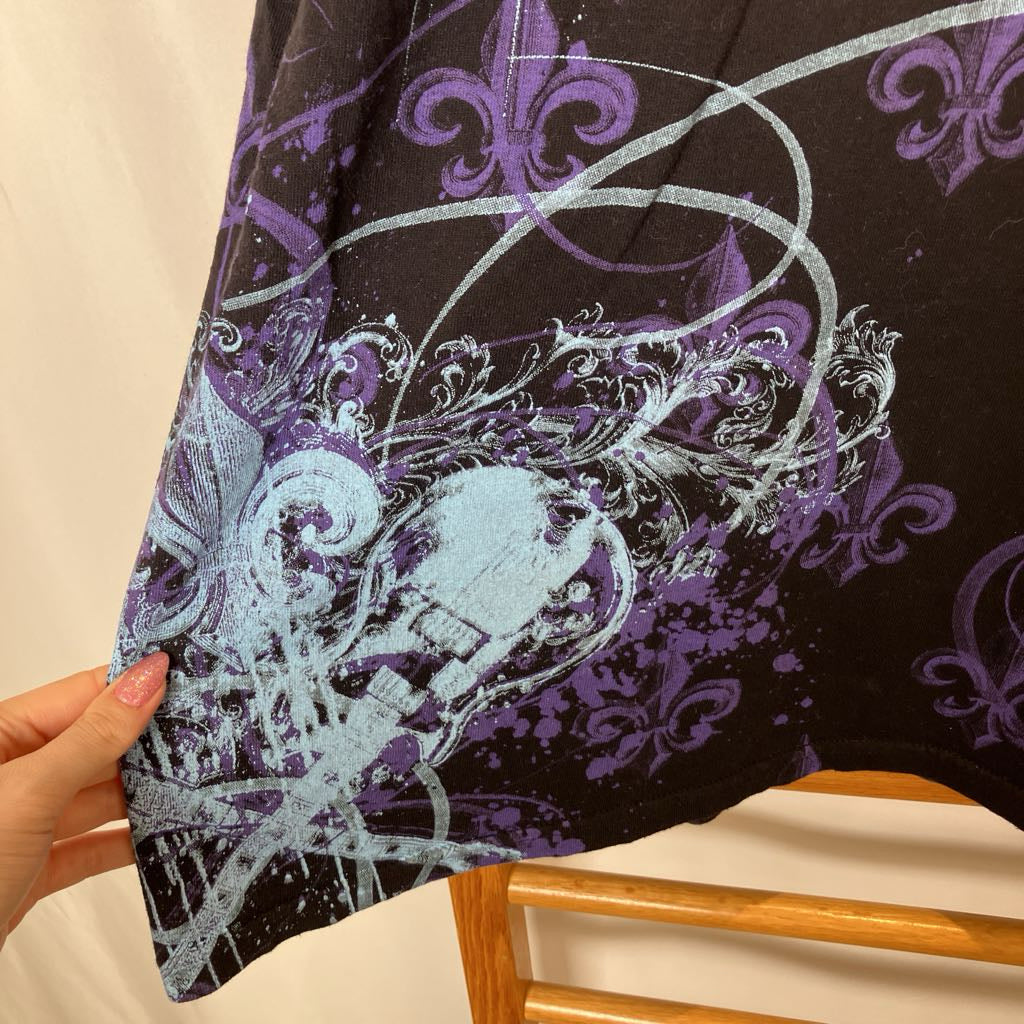 Close-up of a fabric with intricate purple and white patterns held by a hand.