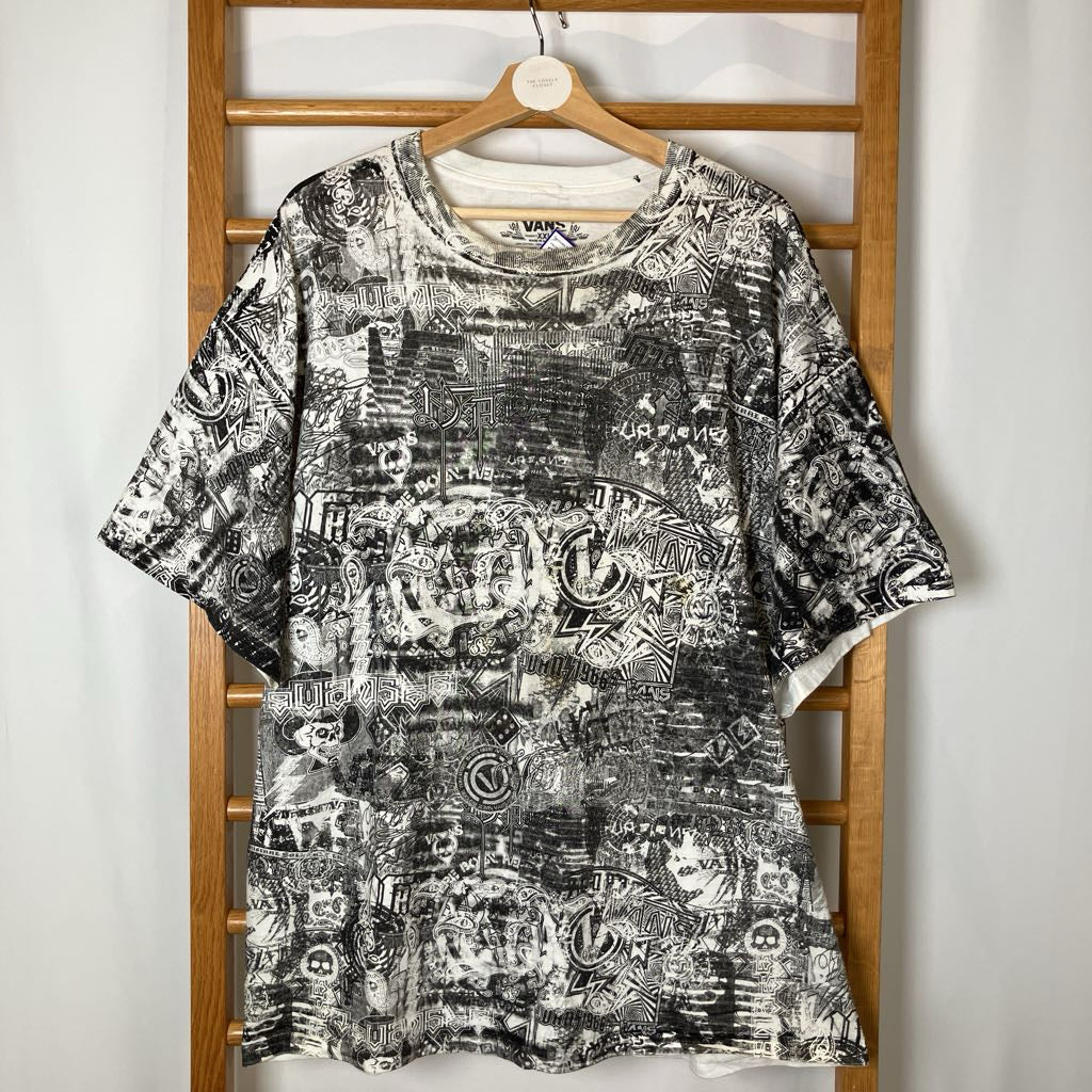 Black and white patterned t-shirt on a wooden hanger against a white wall