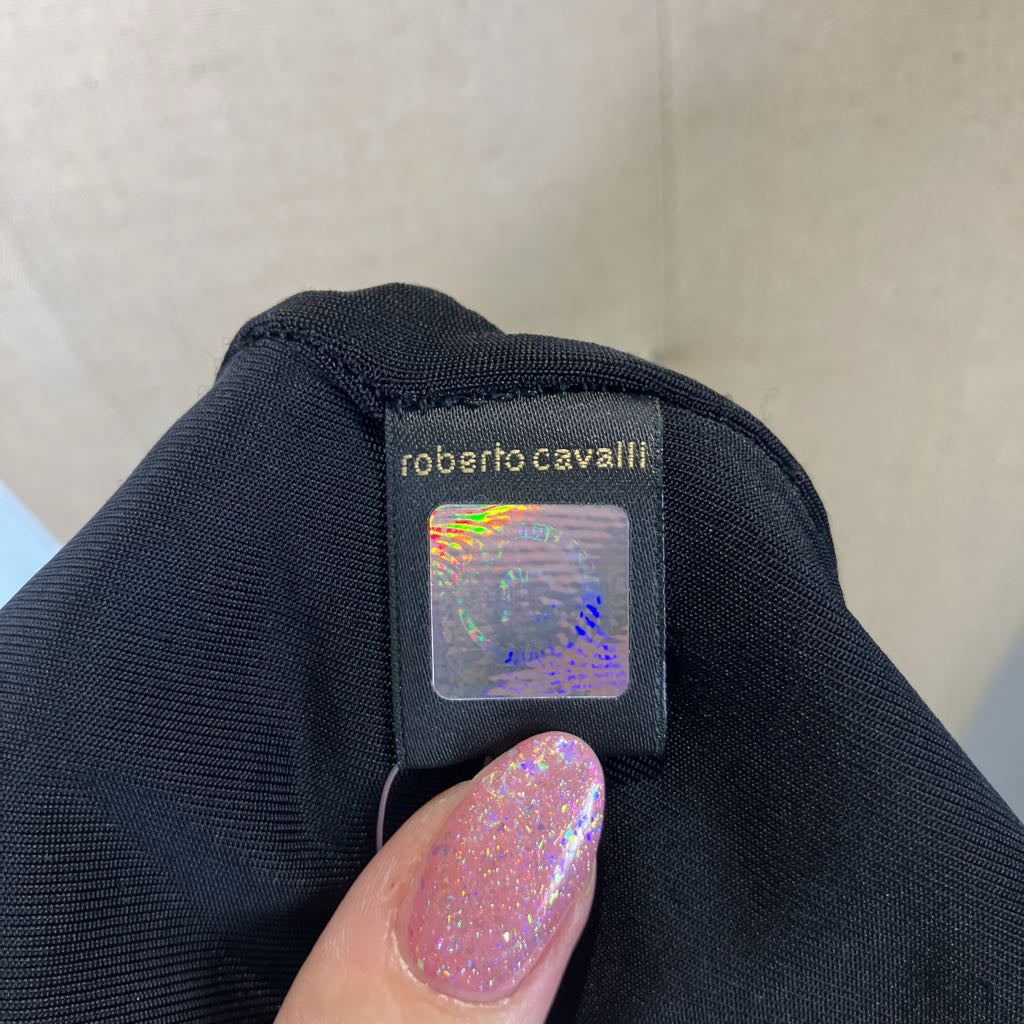 Roberto Cavalli label on a black garment with a hand holding it.