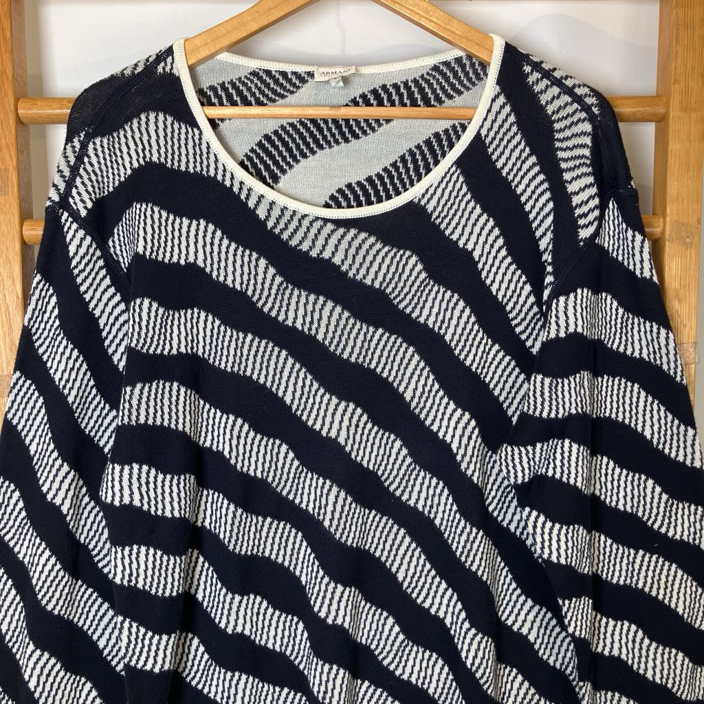 Black and white striped sweater on a wooden hanger against a white wall.