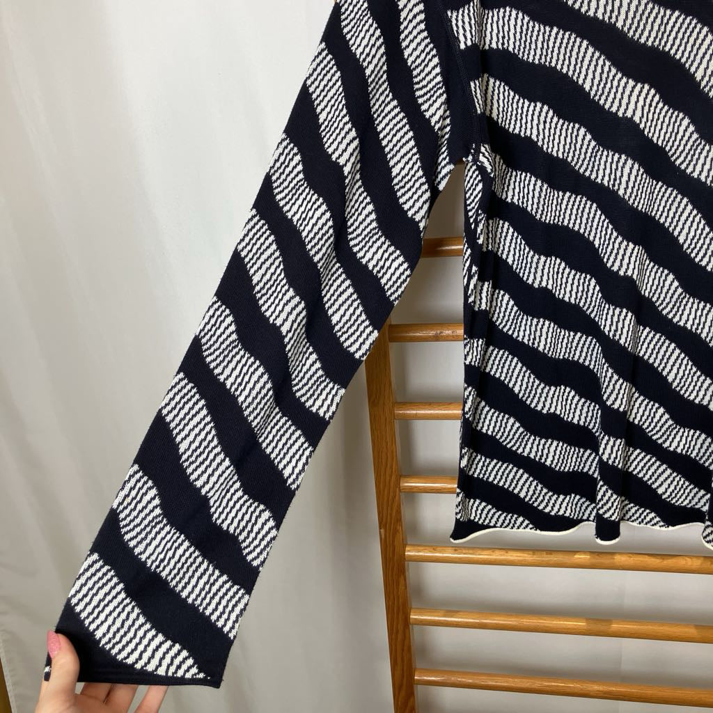 Black and white striped sweater sleeve held up against a neutral background