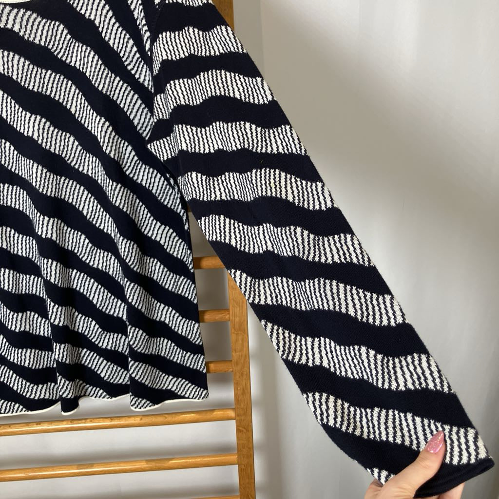 Black and white striped fabric draped over a wooden chair against a plain background