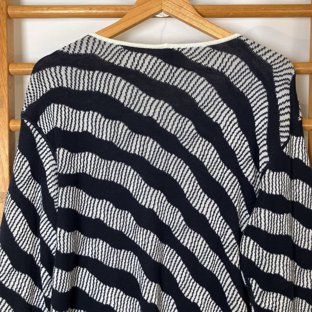 Black and white striped sweater on a wooden hanger against a white background