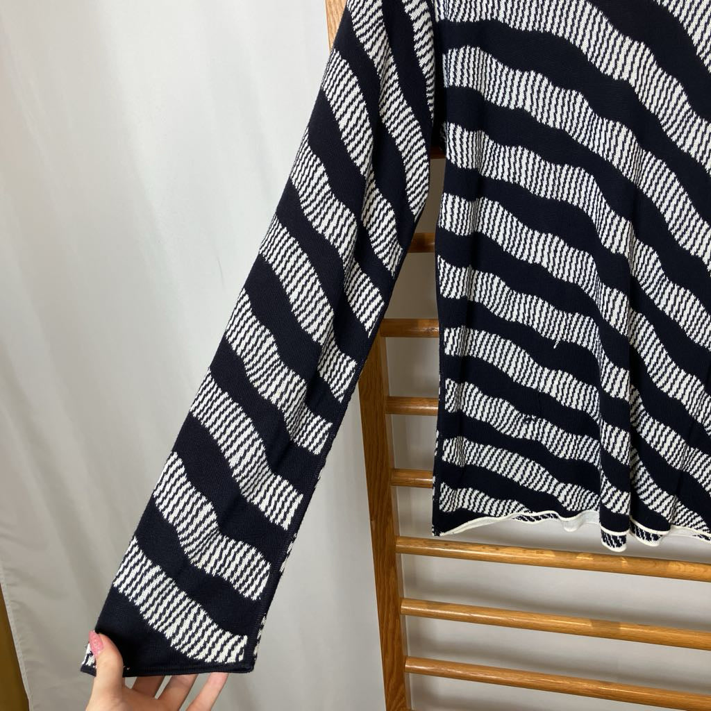 Black and white striped fabric draped over a wooden rack against a plain background