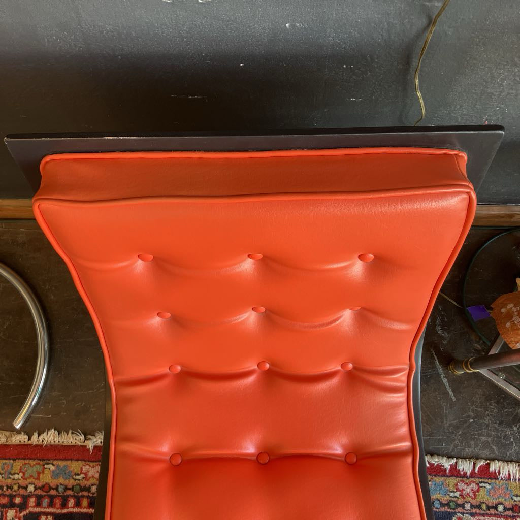 Orange mcm tufted vinyl scoop chair with walnut wood frame  that has been painted black 