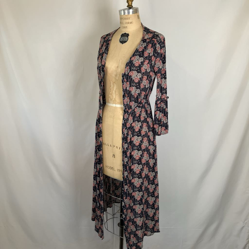 A long-sleeve floral kimono-style cardigan displayed on a vintage dress form mannequin against a white fabric backdrop.