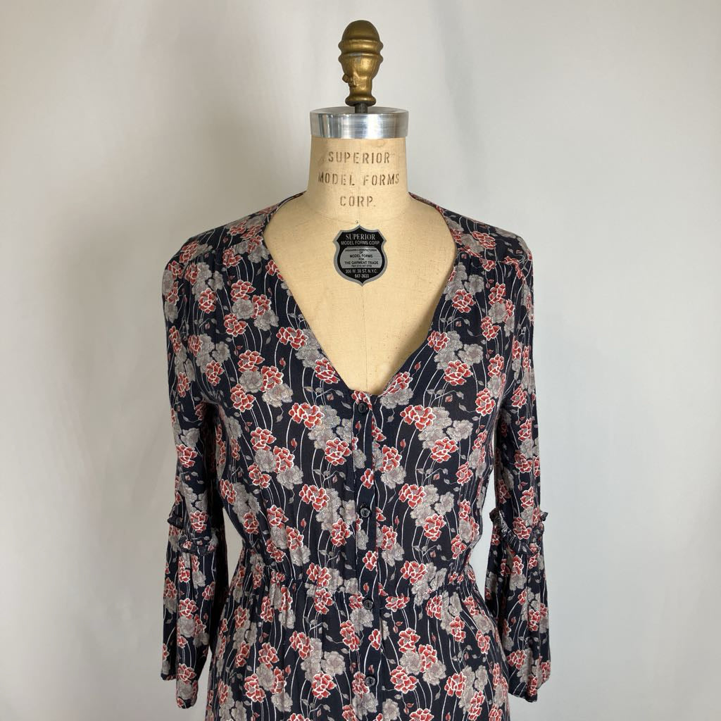 A vintage floral print dress displayed on a vintage wooden model dress form. The dress has a dark navy blue base with a red and gray floral pattern, long sleeves, and a V-neckline.