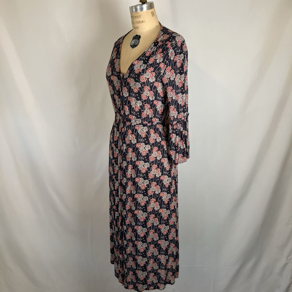 A vintage-style floral midi dress displayed on a dress form mannequin against a white fabric backdrop. The dress features a dark navy blue base with a pink and light blue floral pattern.