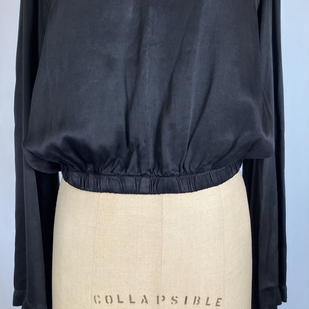 A close-up of a black long-sleeve top with a gathered elastic waist, displayed on a beige dress form that reads 'COLLAPSIBLE'.