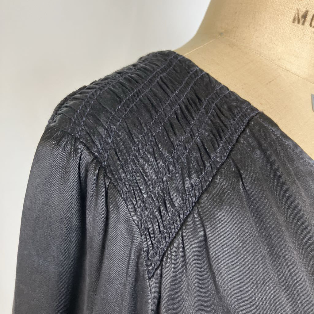 Close-up of a dark charcoal gray blouse with a gathered, smocked shoulder panel, displayed on a tan dress form mannequin.