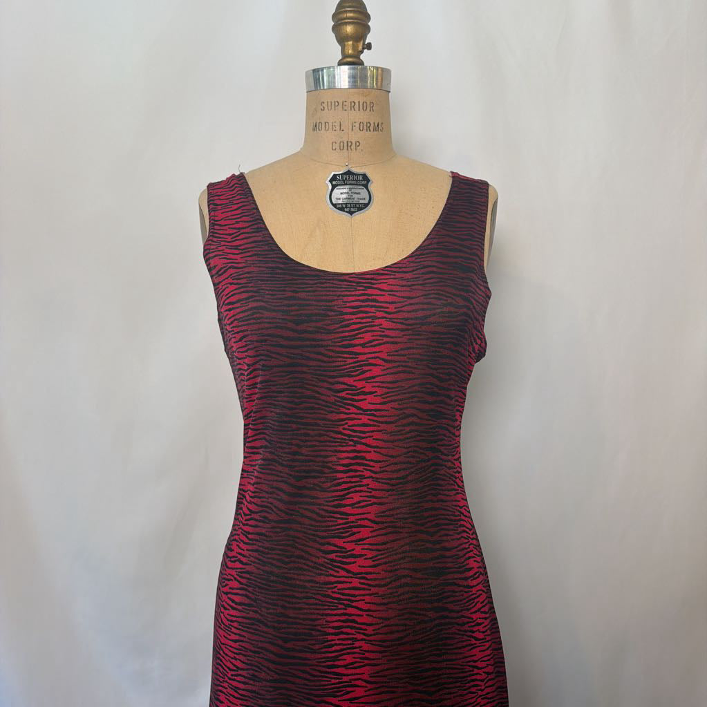 A sleeveless scoop-neck dress with a red and black wavy animal print pattern, displayed on a vintage wooden dress form mannequin against a light gray fabric backdrop.