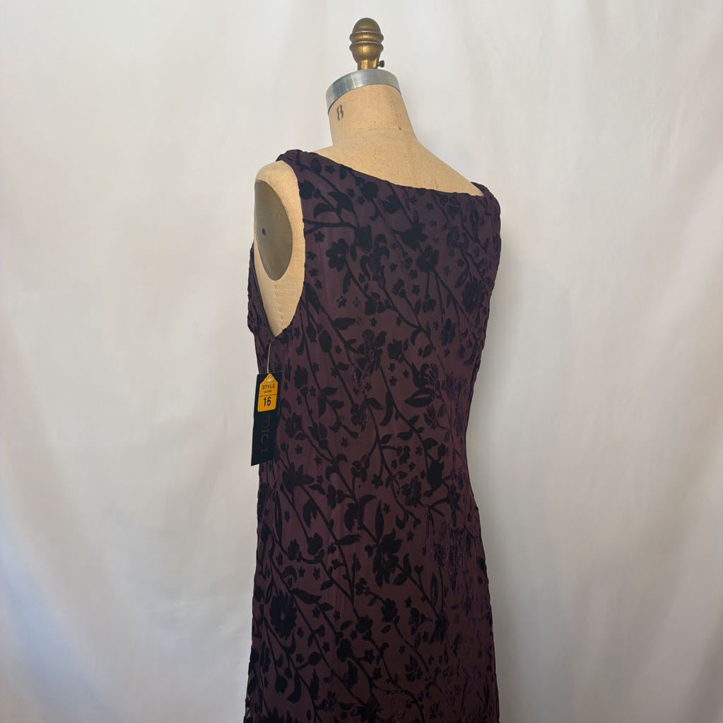 A sleeveless dark plum dress with a black floral pattern, displayed on a beige dress form mannequin against a white fabric backdrop.