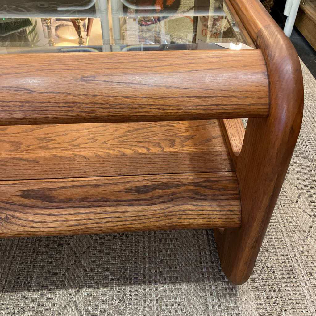 Close-up of a mid-century modern wooden chair with a rich medium-brown wood grain finish, featuring a curved armrest and a glass top surface.