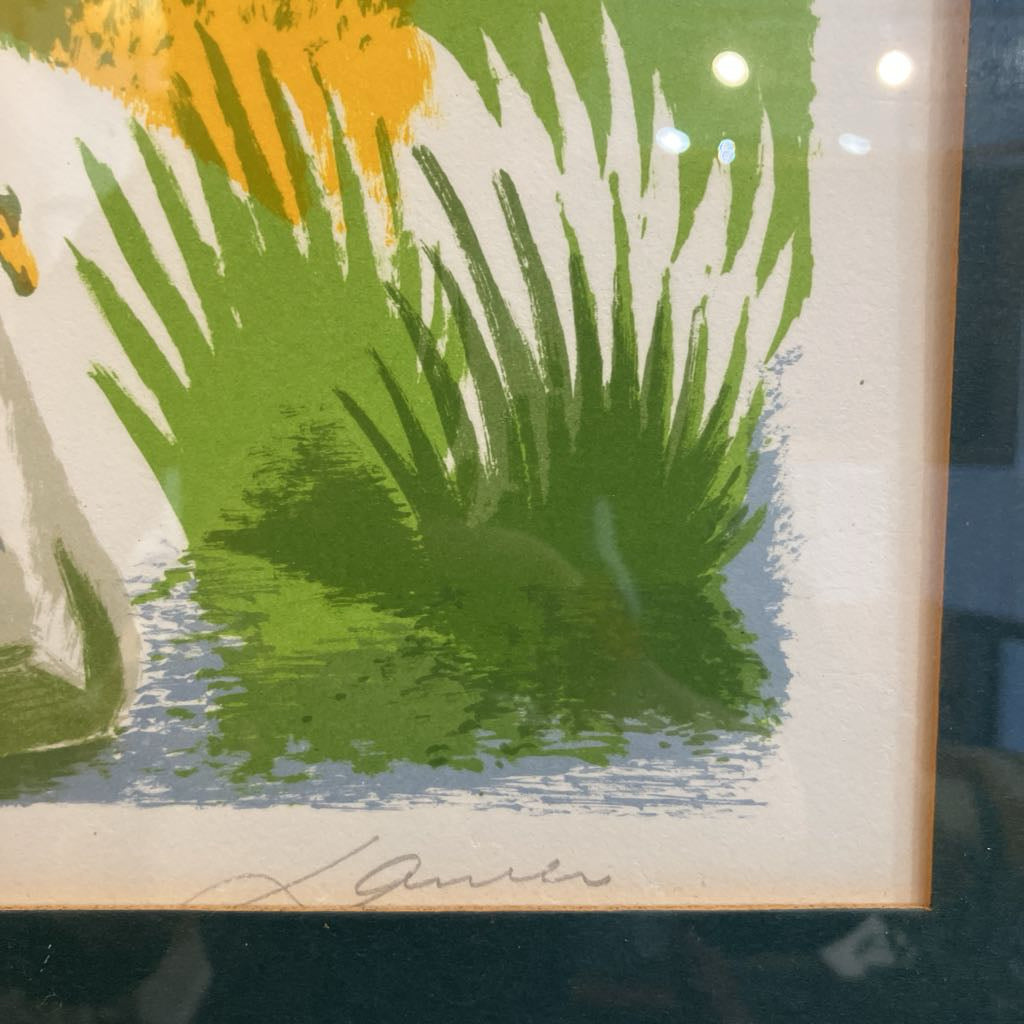 A close-up of a framed art print featuring bold green and yellow abstract plant-like forms on a white background, with a light blue textured base and a signature near the bottom.
