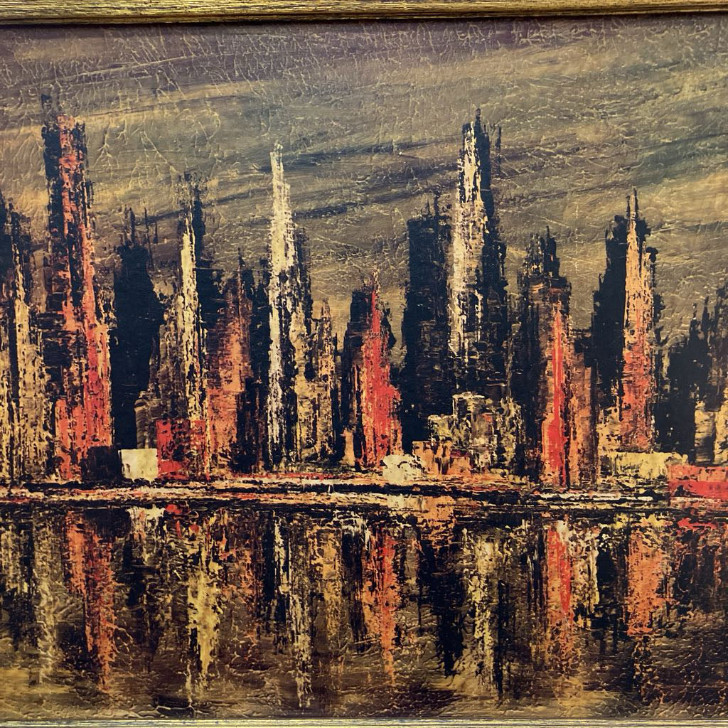 An abstract cityscape painting featuring tall skyscrapers in black, red, white, and brown tones, with their reflections visible in the water below, housed in a gold-toned frame.