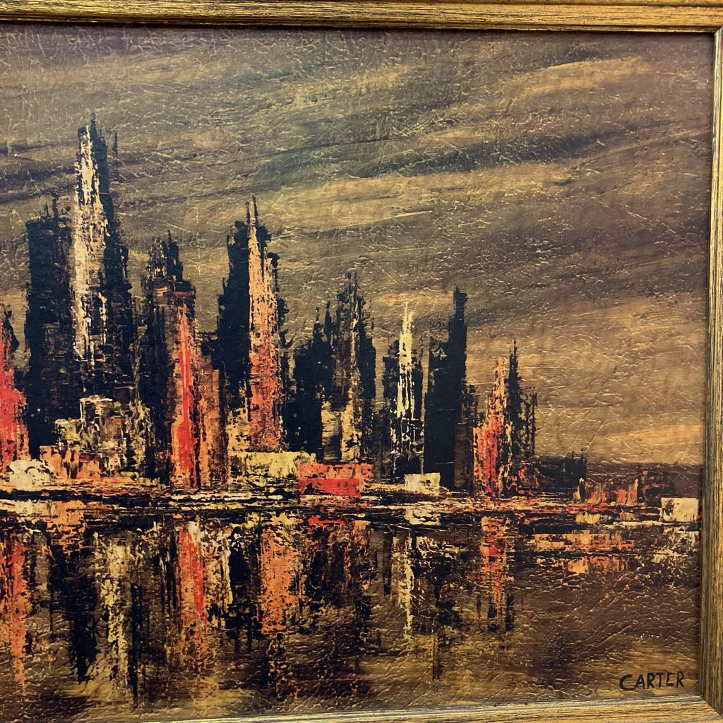 An oil painting of a city skyline with tall dark buildings reflecting in water, signed CARTER in the bottom right corner and housed in a wooden frame.