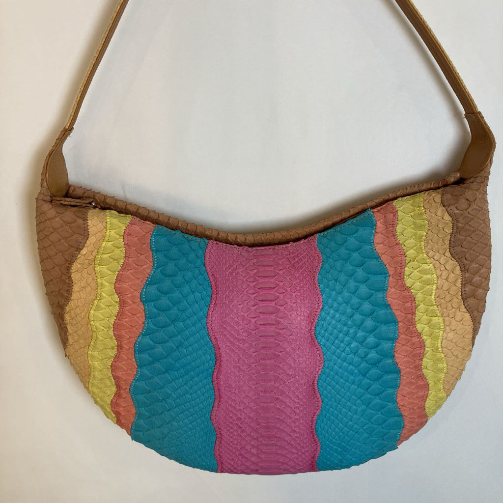 A crescent-shaped shoulder bag with a multicolor striped pattern featuring turquoise, magenta, coral, yellow, and tan textured scales, finished with tan leather trim and strap.