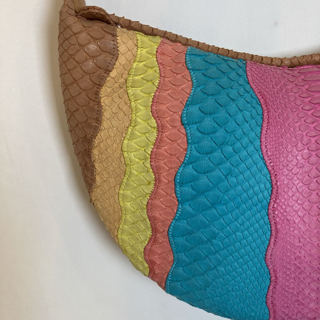 A close-up of a handbag with a wavy, scalloped edge and a multicolor quilted body featuring vertical stripes of brown, tan, yellow-green, coral pink, turquoise blue, and magenta on a textured leather-like finish.