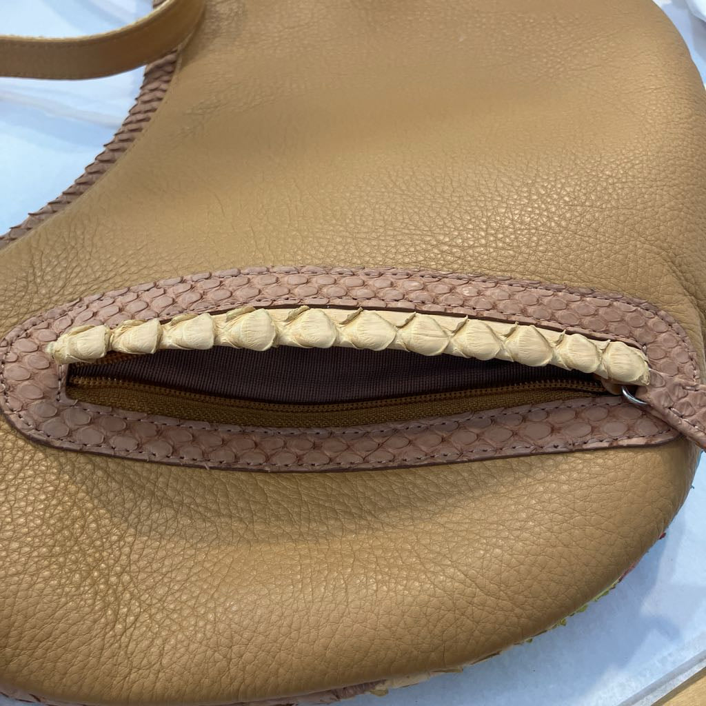 Close-up of a tan pebbled leather bag with a zippered pocket featuring a braided beige trim and zipper pull.