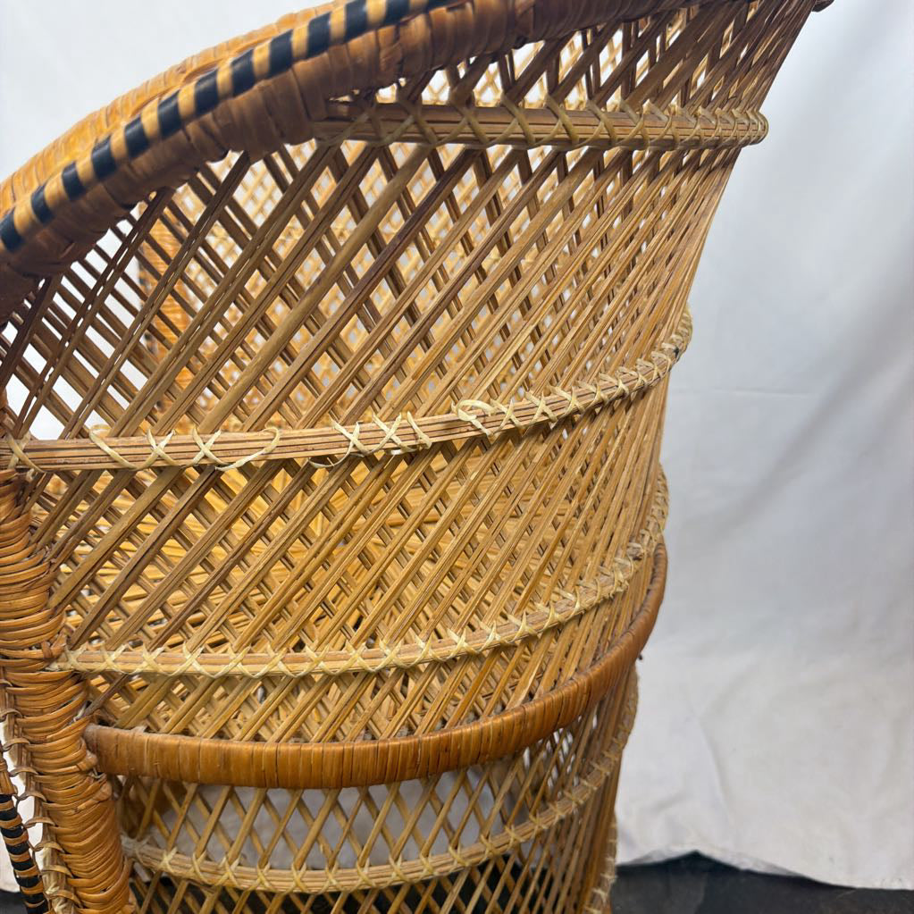 Close-up of a woven rattan chair back showing the natural tan material and diamond-pattern weave, with a white fabric backdrop in the background.