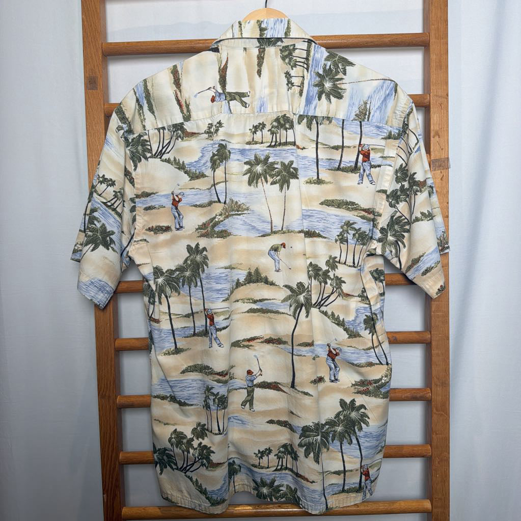 A short-sleeve camp collar button-up shirt with a golf course landscape print, hanging on a wooden hanger on a wooden ladder against a white curtain background.