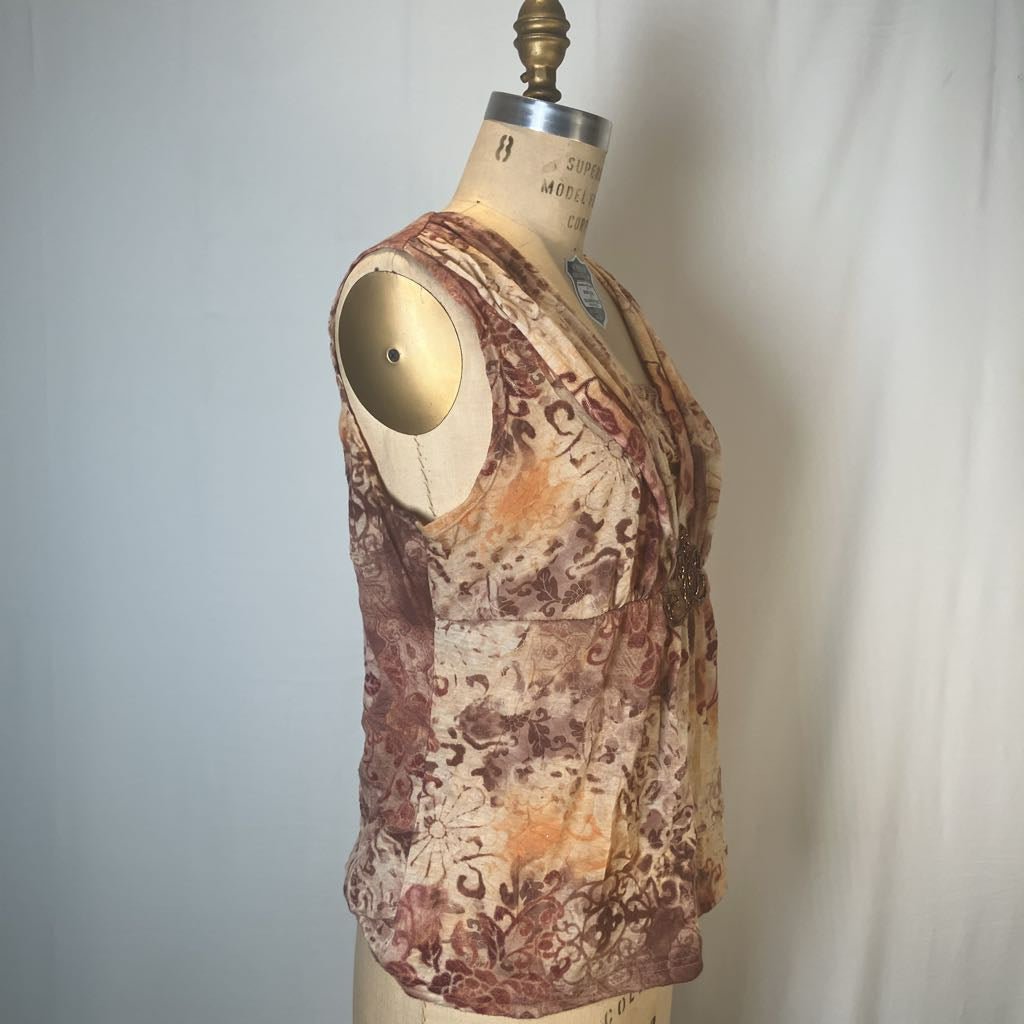 A sleeveless V-neck top with a brown and beige abstract floral pattern, displayed on a vintage dress form mannequin against a white fabric backdrop.