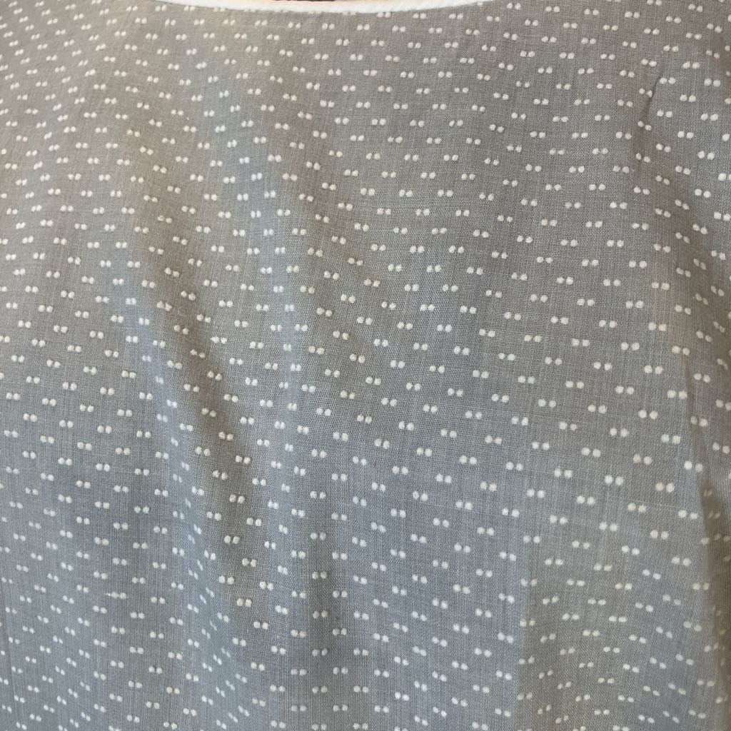 A close-up of a gray fabric with a repeating pattern of small white dots.