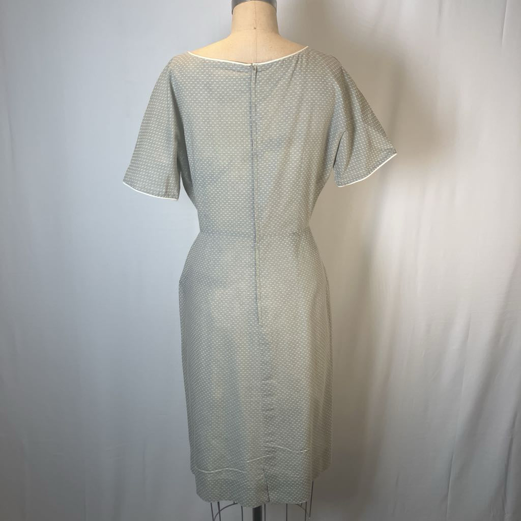 A short-sleeve knee-length dress with a fine micro-dot pattern in light gray and white, displayed on a dress form against a white fabric backdrop.