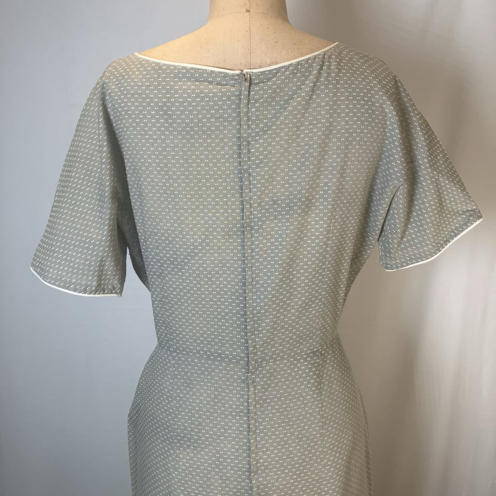 A short-sleeve dress displayed on a mannequin torso, featuring a light gray and white micro-pattern with white piped trim on the sleeve cuffs and neckline.