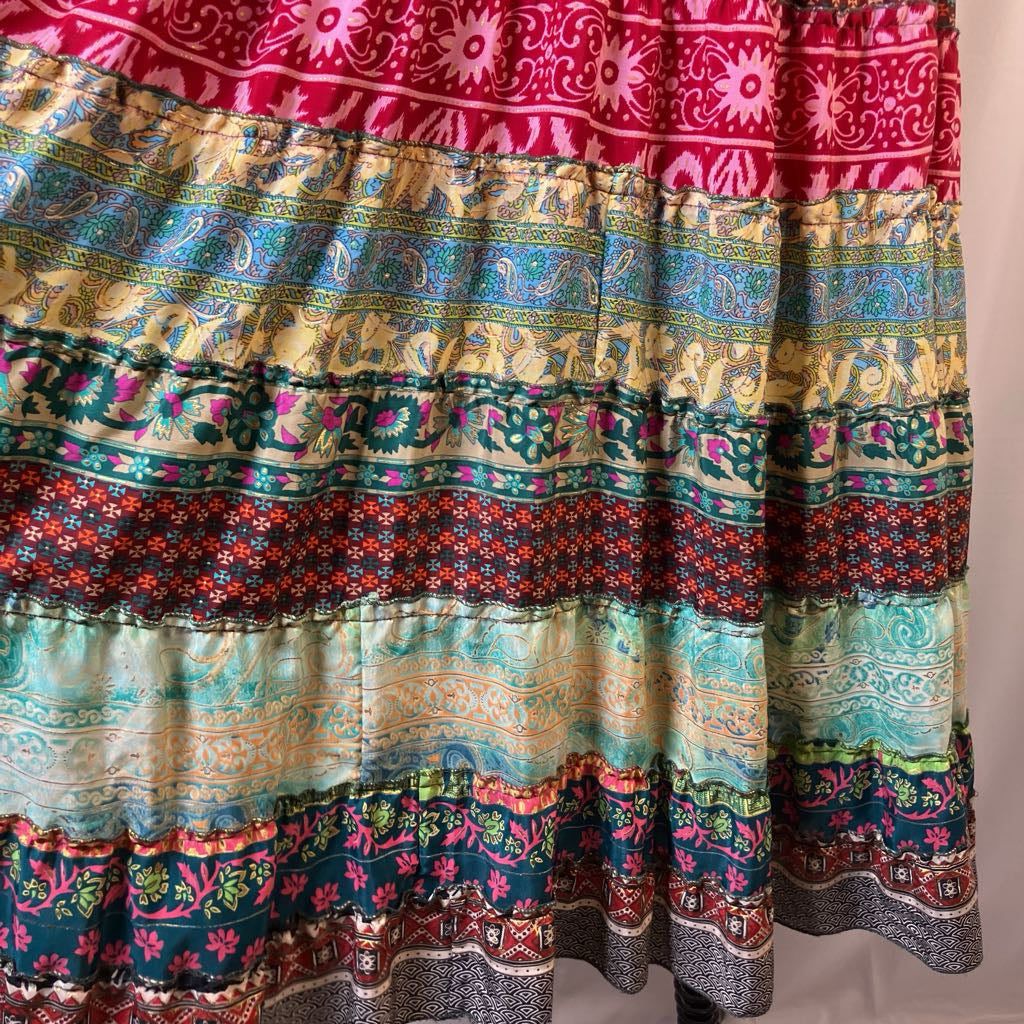 A tiered bohemian-style maxi skirt featuring a vibrant multicolor patchwork print with intricate floral, paisley, and geometric patterns in red, blue, green, yellow, and beige.