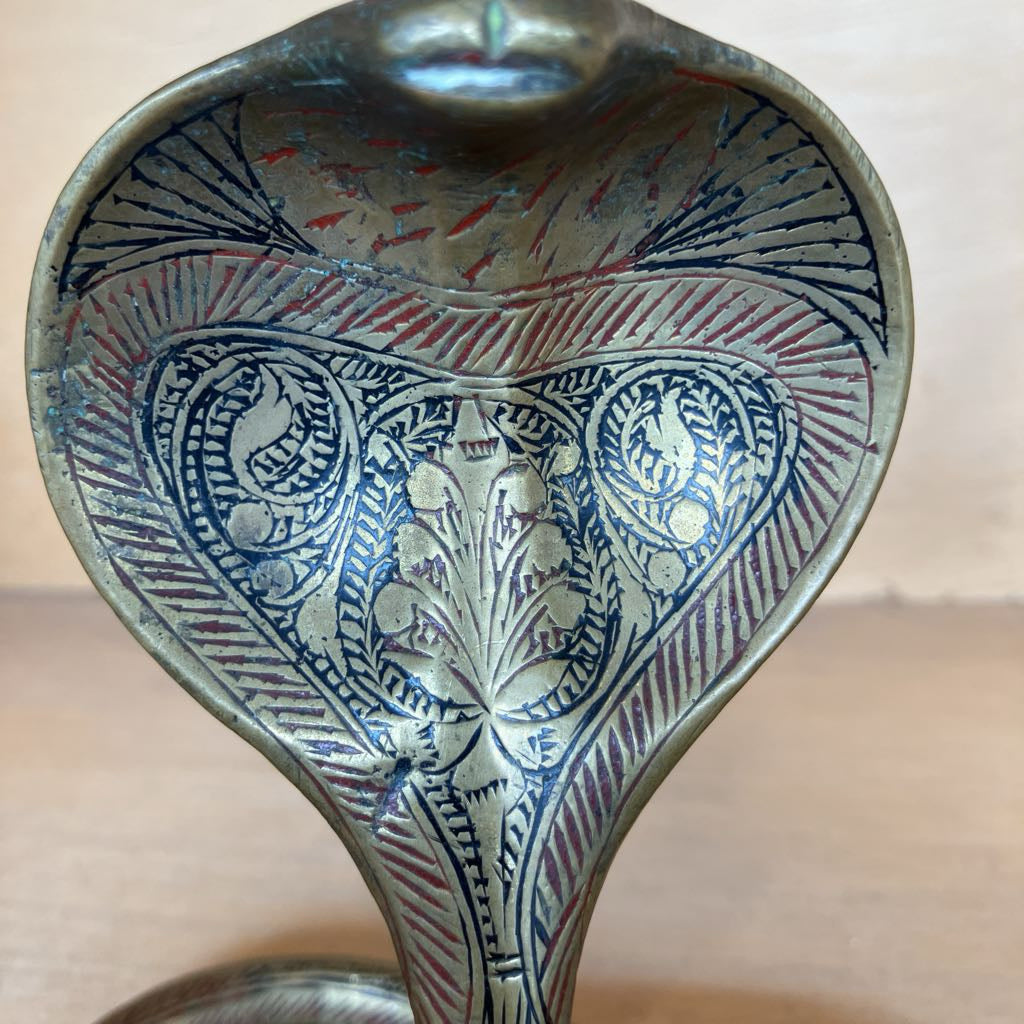 An ornate metal candleholder with a cobra-inspired hooded shape, featuring intricate hand-painted blue and red floral and geometric patterns on a silver-toned metallic surface.
