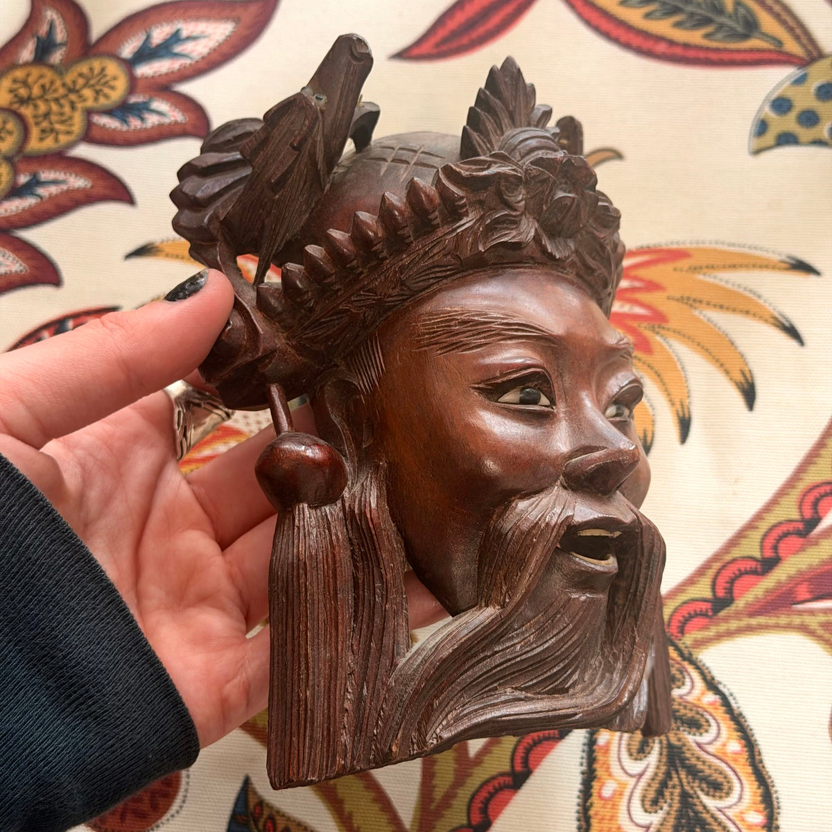 Carved Wood Face with Dragons against a patterned background