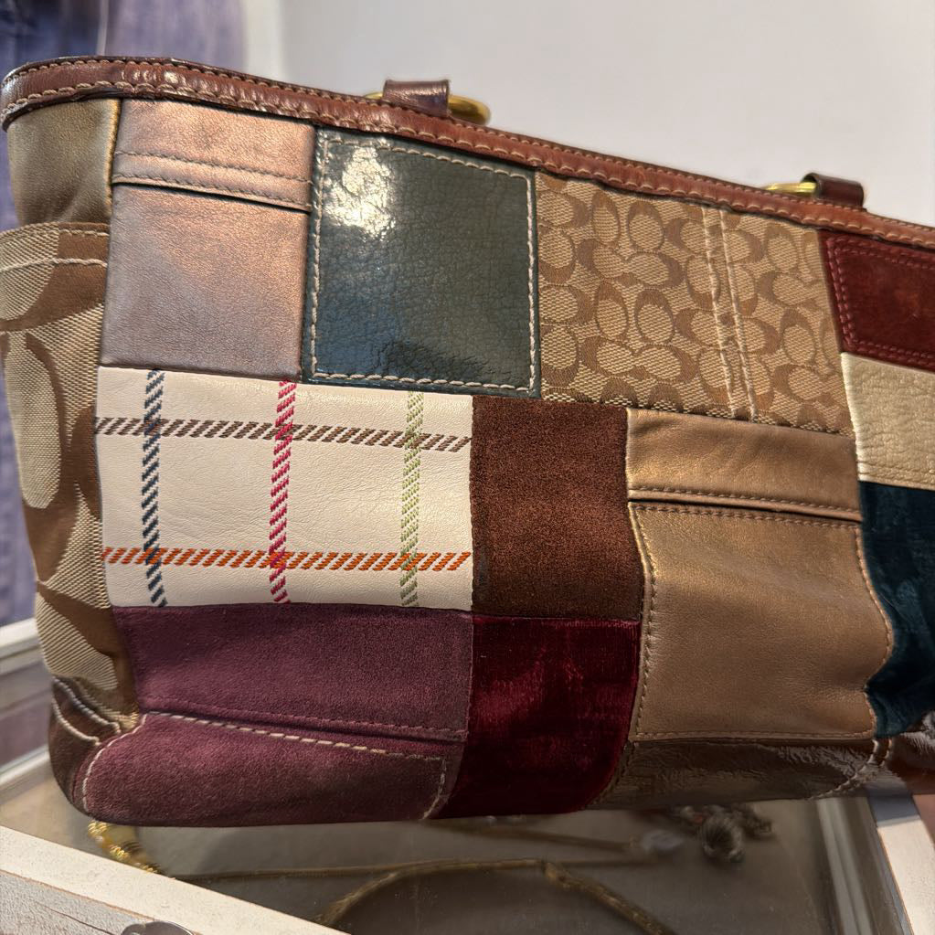 A Coach patchwork shoulder bag featuring multiple panels of signature monogram canvas, plaid, smooth leather, and velvet in shades of beige, brown, burgundy, and teal.