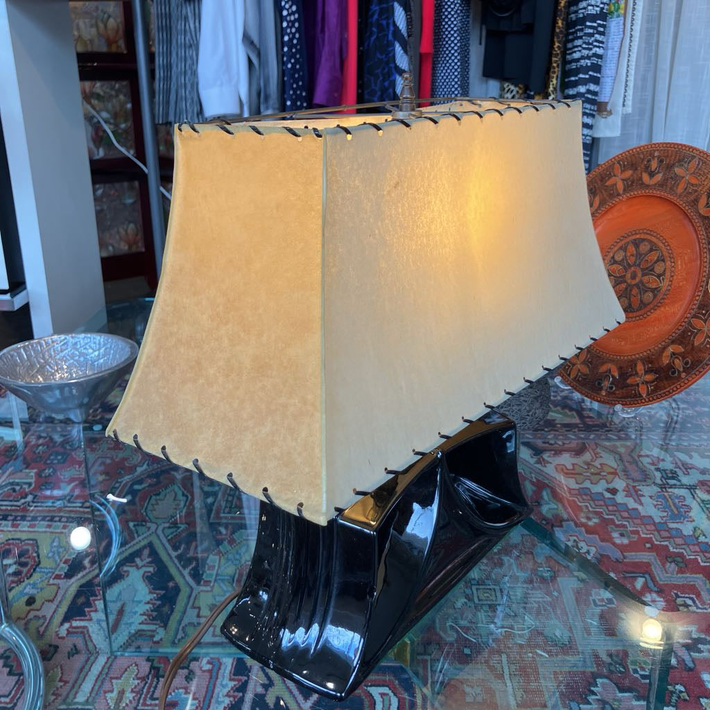 Mid-century lamp with a black ceramic angular base and a larger trapezoidal shade in a store setting. 