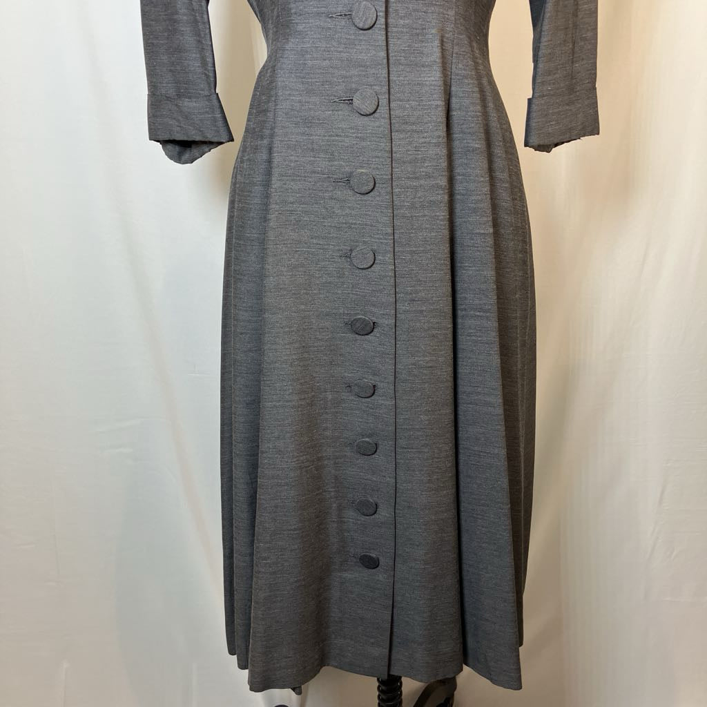 A gray long-sleeve midi dress with a button-down front, displayed on a dress form against a white fabric backdrop.
