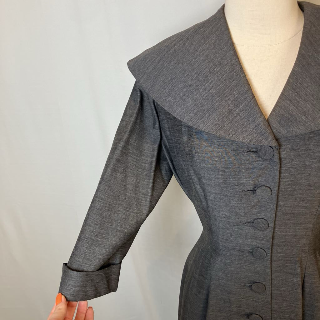 A gray long-sleeve dress or coat with a wide collar and dark buttons, shown on a mannequin against a plain light background.