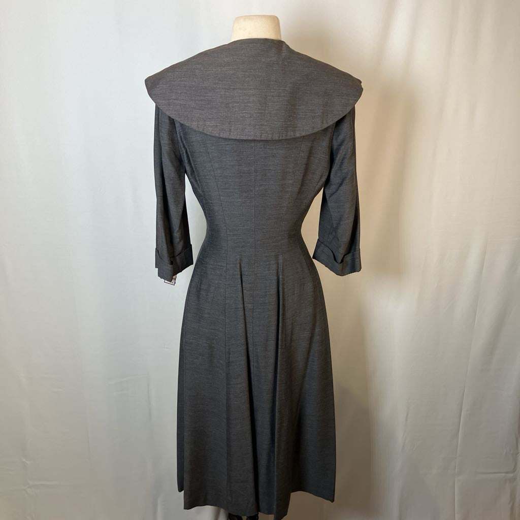 A dark gray textured dress with a wide collar and three-quarter sleeves, displayed on a mannequin against a white fabric backdrop.