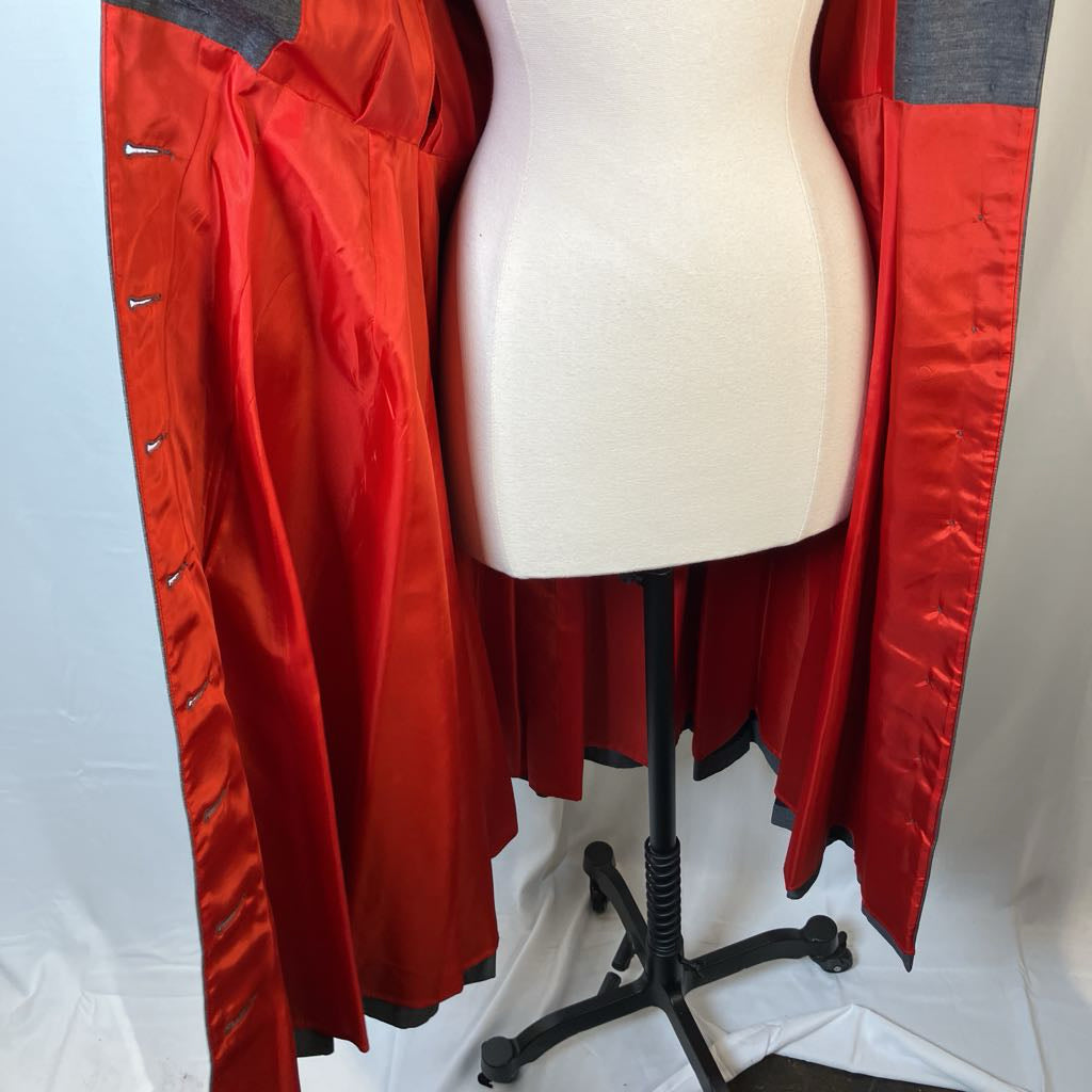 A red satin-like garment or robe with gray shoulder panels is displayed on a cream dress form mannequin against a white studio backdrop.