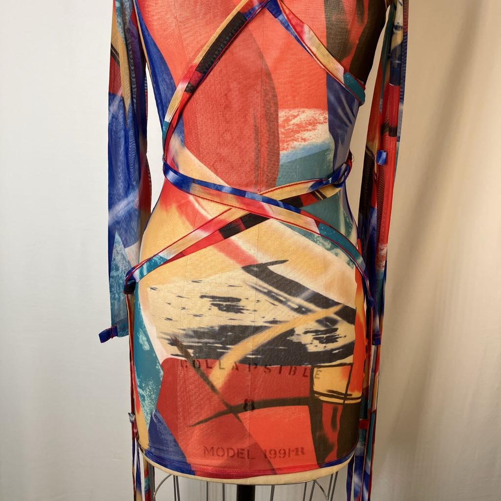 A long-sleeve wrap-style dress with an abstract brushstroke print in red, orange, blue, beige, and black, displayed on a dress form against a plain light background.