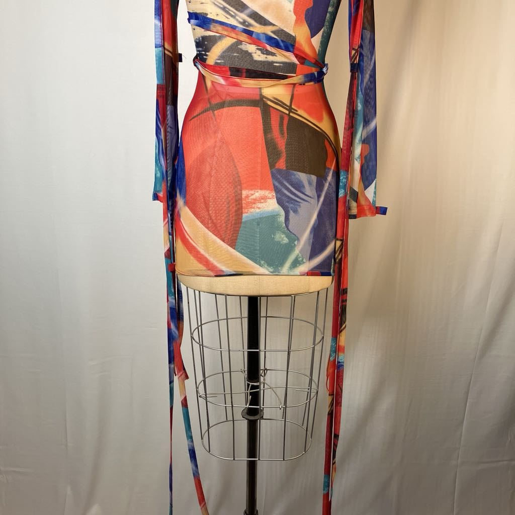 A long-sleeve wrap dress with an abstract multicolor print, displayed on a wire dress form against a white fabric backdrop.