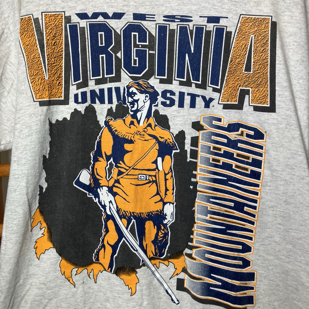 Close-up of a heather gray graphic t-shirt featuring the West Virginia University Mountaineers design in navy blue and orange.